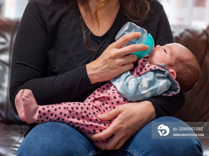 Mother bottle feeding infant daughter