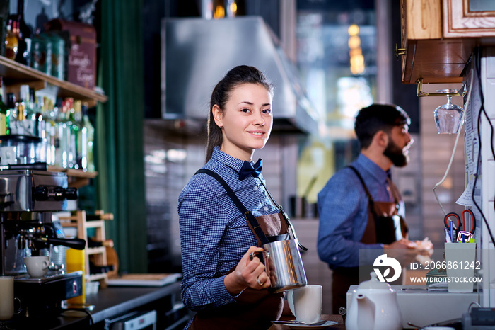 Girl barista bartender waiter in uniform making coffee at the bar.