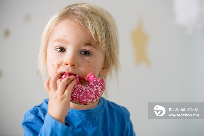 Cute sweet blonde child, playing and eating donuts