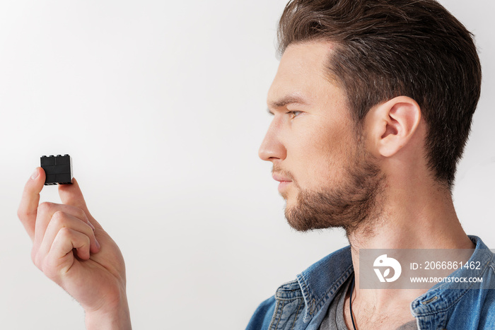 Thoughtful adult male person keeping figurine