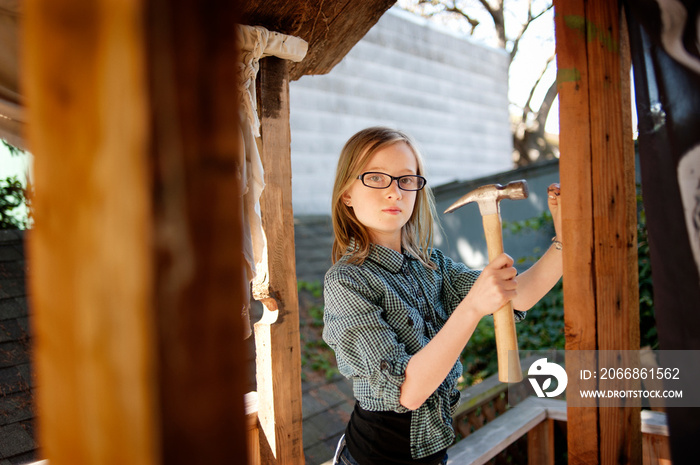 Portrait of girl hitting nail with hammer