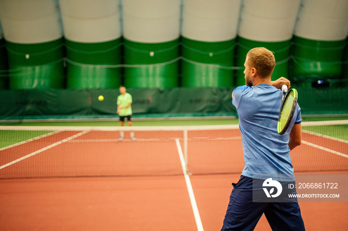 Instructor or coach teaching how to play tennis on a court indoor