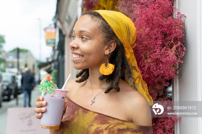 Portrait of young woman drinking smoothie in city