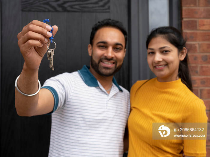 Portrait of smiling couple holding keys to house