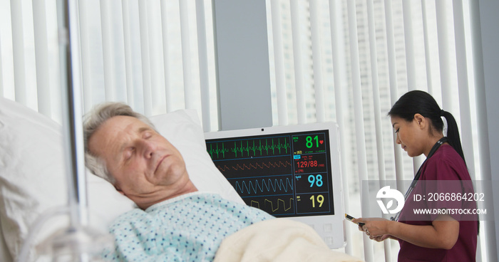 Doctor standing in window of hospital room text messaging family on mobile phone while patient recovers in bed. Senior man in foreground with surgeon updating loved ones in background