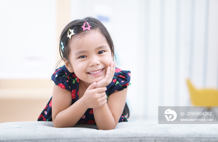 Asian children or kid girl and student thinking for new idea and happy fun or smile white teeth and hand to cheek with stick hairpin at kindergarten classroom or nursery and child hospital or school