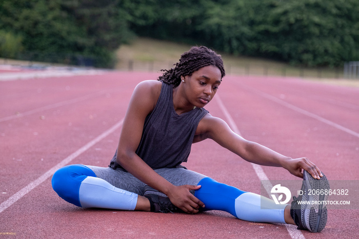 Athletic�woman stretching leg on running track