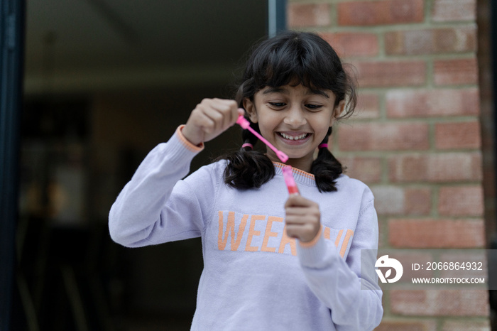 Little girls playing with bubble wand outdoors