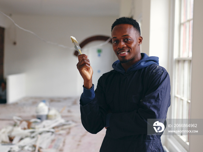 Portrait of smiling man holding paintbrush during renovation