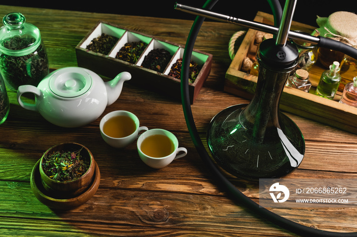 Top view of tea and hookah on wooden surface isolated on black.