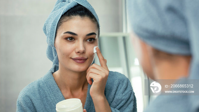 Reflection in a mirror beautiful woman making cosmetic skin care