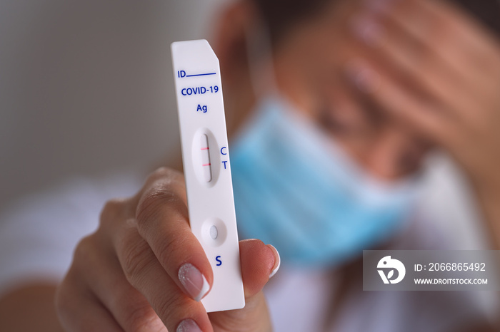 Sick infected woman showing rapid covid antigen test or express covid test with positive covid-19 result. Woman with coronavirus infection