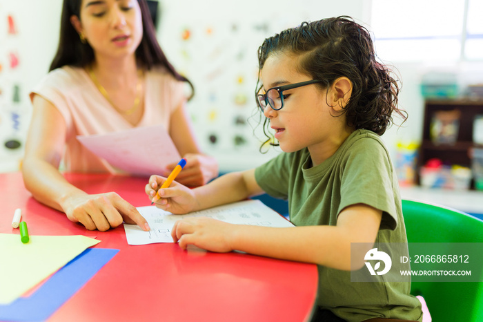 Student boy in kindergarten doing school work and writing