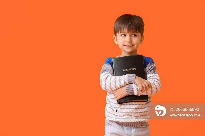 Little boy with Bible on color background