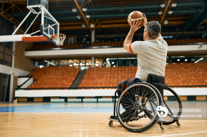 Rear view of basketball player in wheelchair taking a shot on the court.