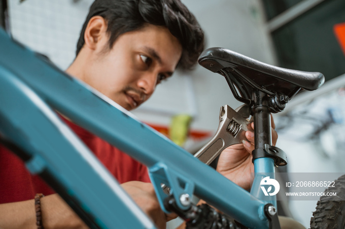 close up of a mechanic installing and tightening seatpost screws using a wrench