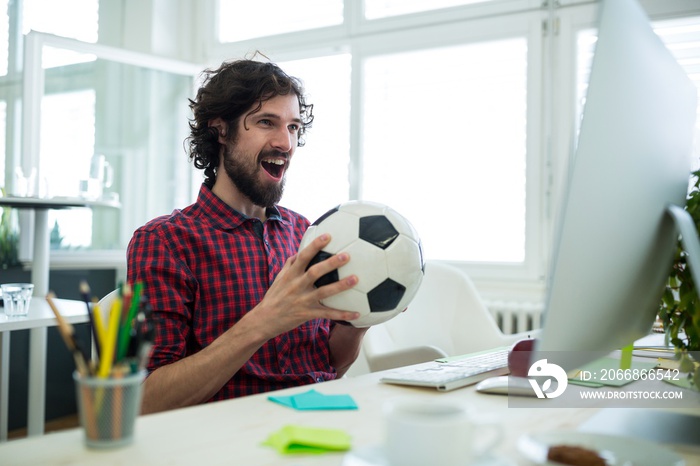 Business executive watching a football match on computer