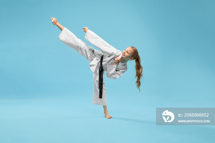 Girl in kimono practicing kick foot forward.