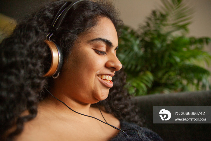 Close up portrait of curvy Indian girl with Cerebral Palsy with headphones  in living room