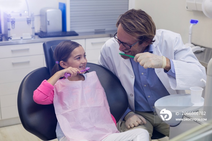 Smiling dentist and patient brushing their teeth