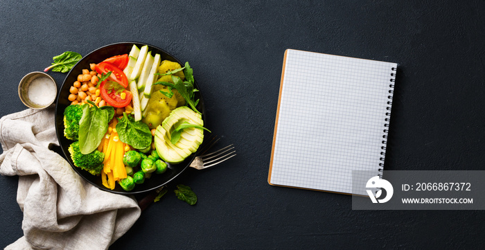 Vegan healthy balanced diet concept. Vegetarian buddha bowl with blank notebook. Сhickpeas, broccoli, pepper, tomato, spinach, arugula and avocado in plate on dark background. Top view