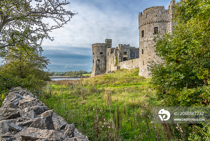 A view towards the Carew estuary between a dry stone wall and the ruins of Carew Castle, Pembrokeshire, UK