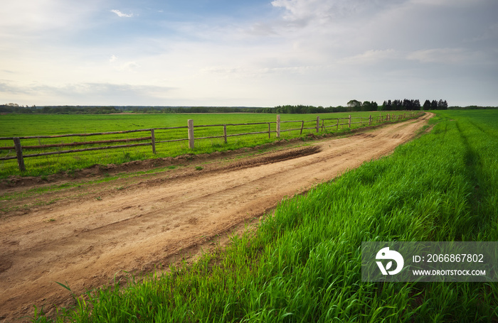 Rural environment with wooden fence beside the road. Spring Landscape