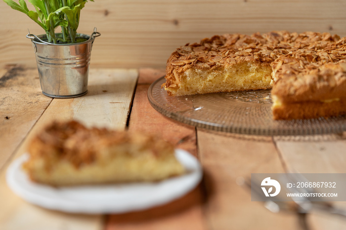 gebackener Bienenstich als Torte mit Füllung aus Creme auf Tisch aus Holz