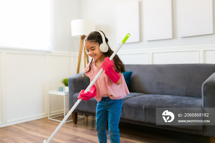 Happy little kid doing house chores while listening to music