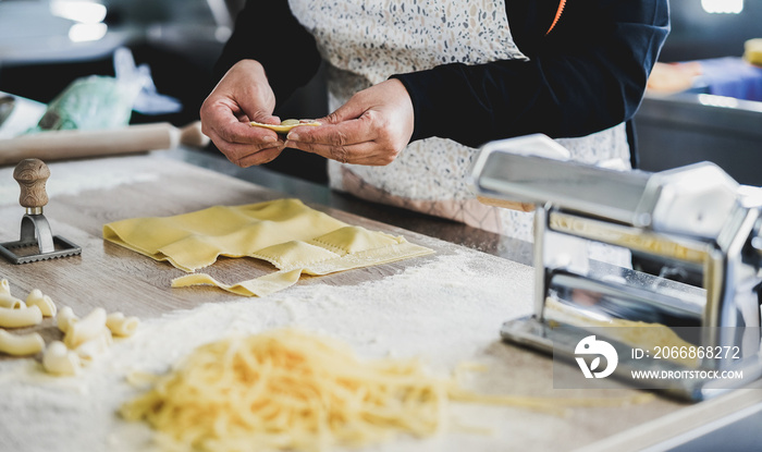 Woman prepare fresh ravioli inside pasta factory - Focus on hands