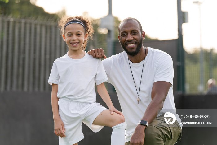 Portrait of man and girl (6-7) wearing soccer uniform