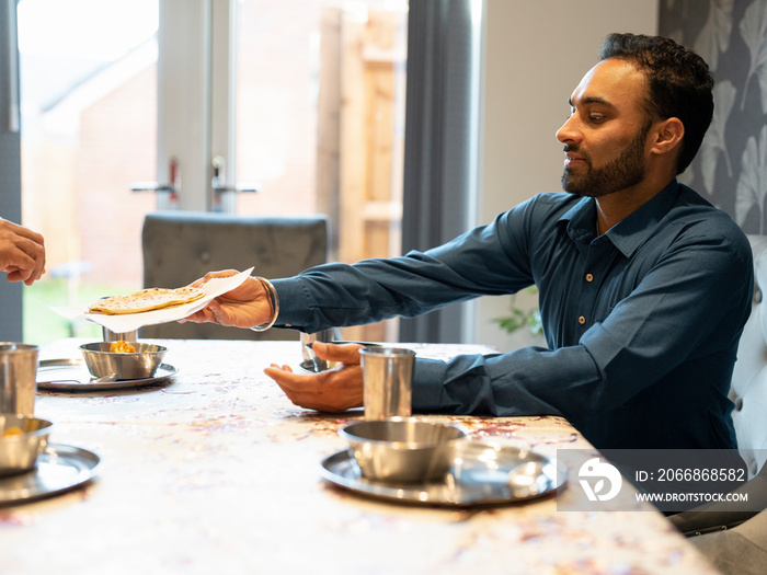 Man sharing naan bread at table