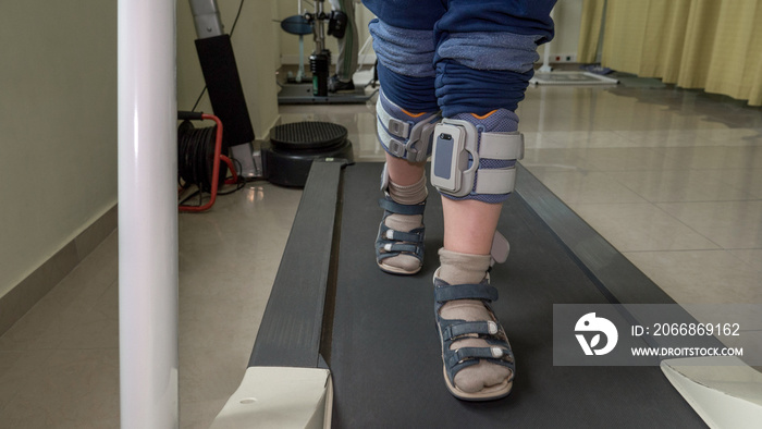 Boy with foot drop system exercising on the treadmill. View to the feet. Treatment with functional electrical stimulation