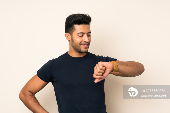 Young handsome man over isolated background looking the wrist watch