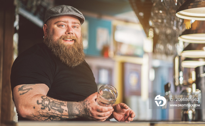 Cheerful tattooed bartender standing with smile