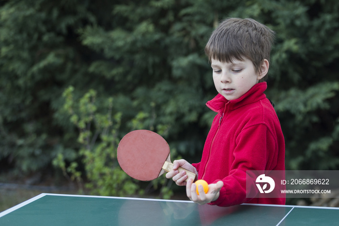 Ein Junge im roten pullover spielt tischtennis