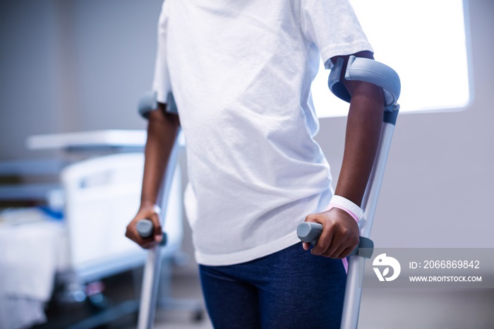 Mid section of girl walking with crutches in ward