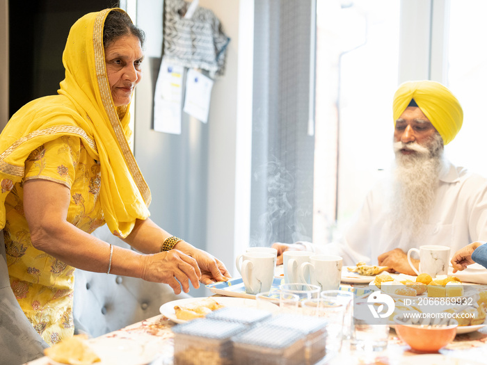 Mature woman in traditional clothing putting chai on table