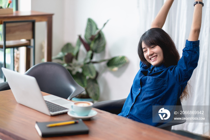 asia woman relax after working,female raise arm up stretching in front of laptop and coffee cup on wood table in cafe restaurant,working lifestyle outside office,chill out leisure