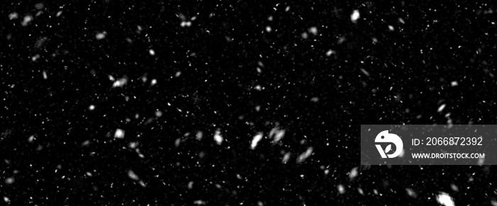 Snowfall bokeh on black background. Many snowflakes in flying in the air. Winte night snowfall and blizzard of snow at. Blur bokeh light effect creative background.