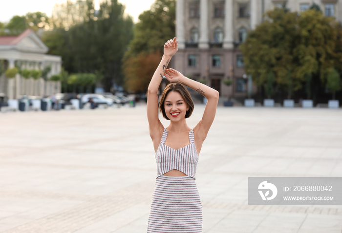 Young beautiful woman posing on city square