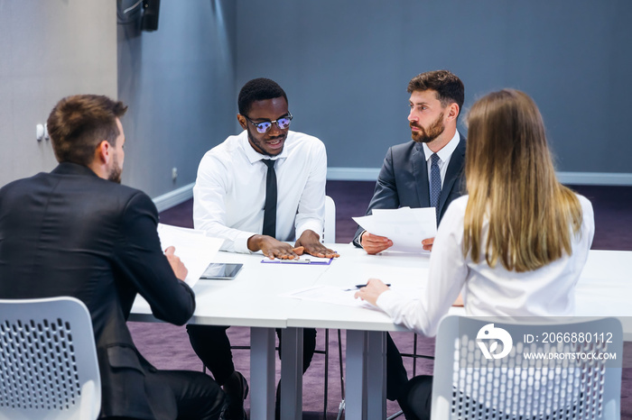 A group of business people, managers share their ideas and discuss a new project in a modern conference hall.