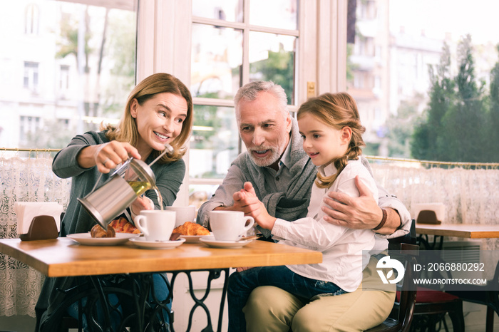 Breakfast in cafeteria. Happy grandparents and cute little girl feeling memorable while having breakfast in cafeteria