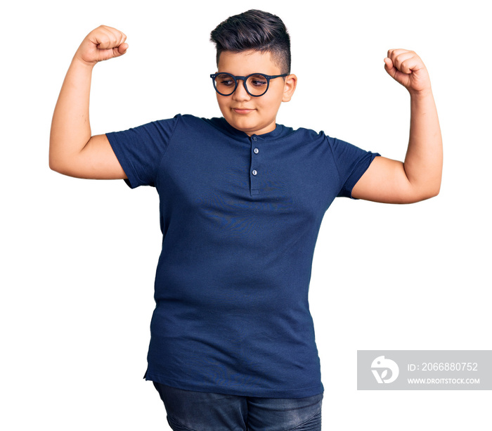 Little boy kid wearing casual clothes and glasses showing arms muscles smiling proud. fitness concept.