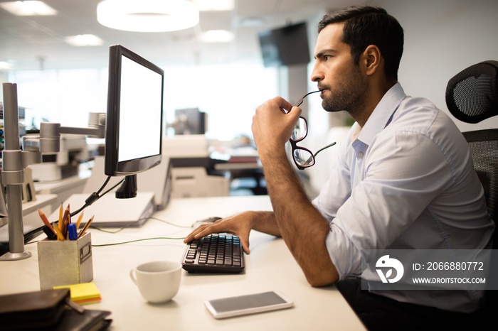 Thoughtful businessman using computer in office