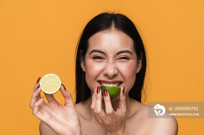 Beauty portrait of young half-naked woman smiling and eating lemon