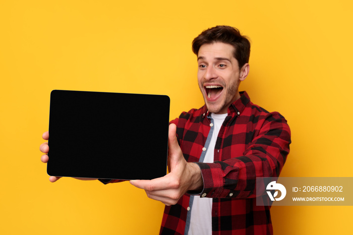 Excited young man showing black empty tablet screen