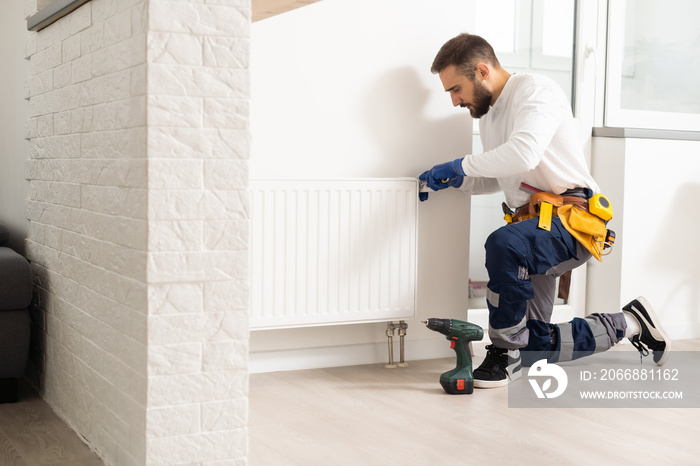 man repairing radiator with wrench. Removing air from the radiator