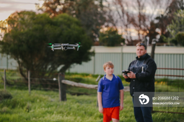 Father and son flying drone on country property