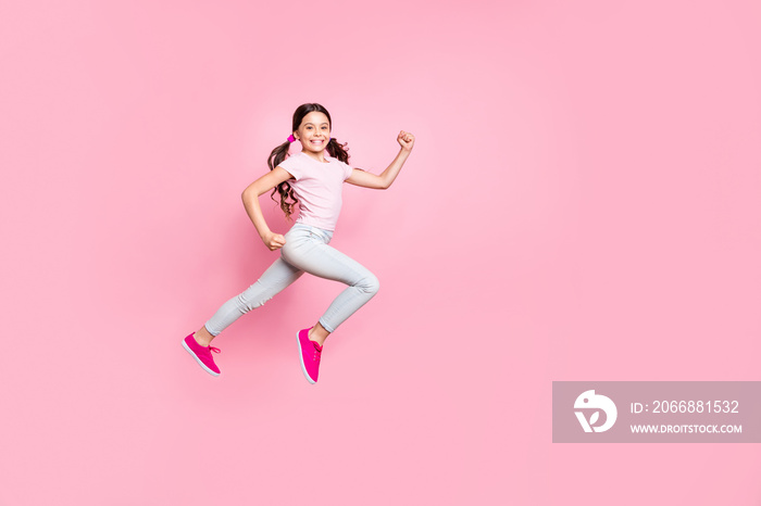 Full length side photo of beautiful little lady jumping high speed race champion dressed casual outfit isolated pink background